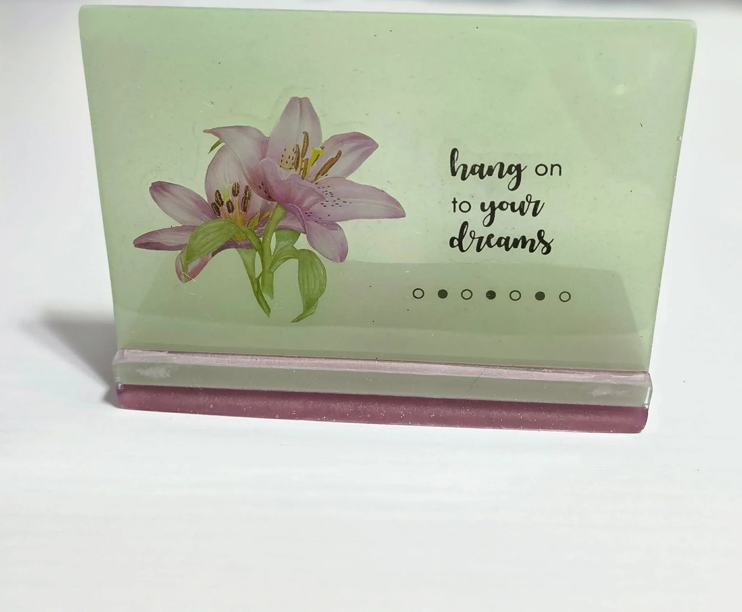 Handcrafted sage green resin plaque with purple lilies and the quote 'hang on to your dreams' on a pink base by Crazy Chaotic Crafter.