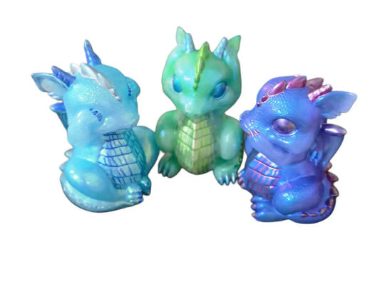A set of three handmade sitting and standing baby resin dragons in blue, mint green, and iridescent purple, created by Crazy Chaotic Crafter