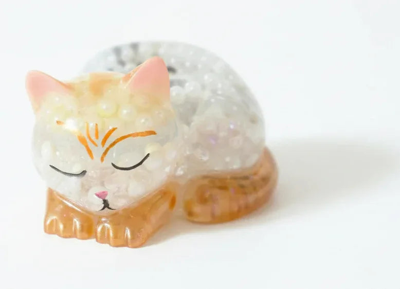 Front View of Handcrafted sleeping cat resin figurine filled with white iridescent pearls and amber translucent accents by Crazy Chaotic Crafter